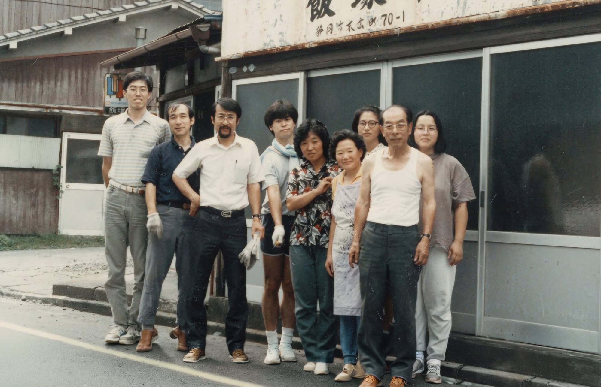 1985年の飯塚印刷の店先に並ぶ、家族と従業員の集合写真
